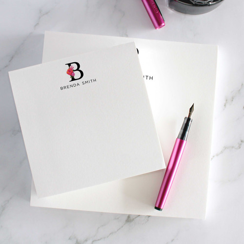 Floral initial notepads with name customization, stacked neatly beside a pink pen for stylish gifting